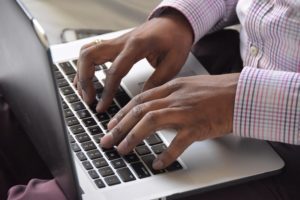 A man types a message on his laptop.